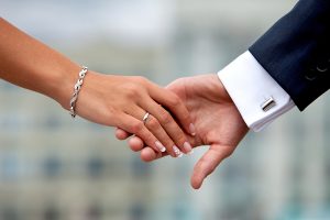 Wedding couple holding hands. Hands, rings, bracelets, cuff links, cuff closeup.