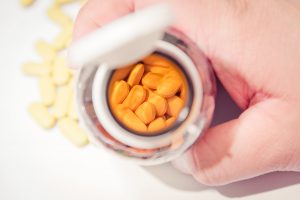 Man holding vitamin brown bottle show tablets of Vitamin inside instagram tone color